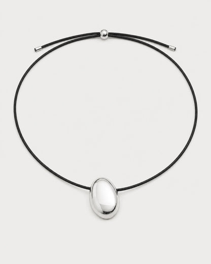 Naiya silver pebble cord necklace on a pale neutral-grey studio background