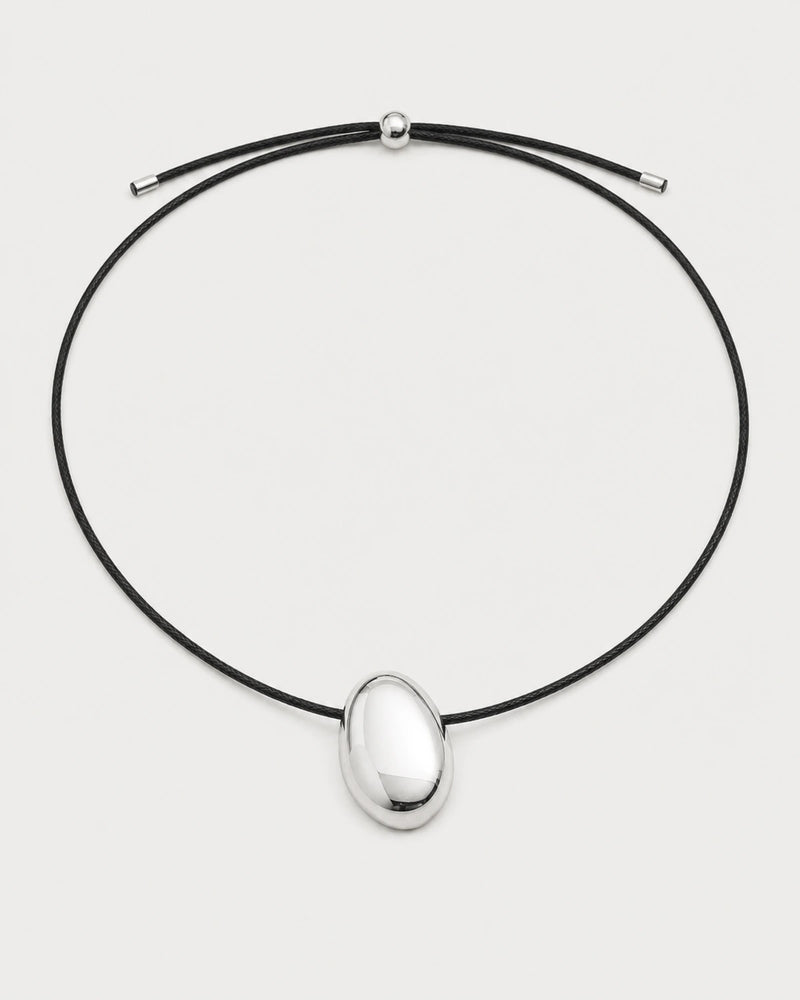 Naiya silver pebble cord necklace on a pale neutral-grey studio background