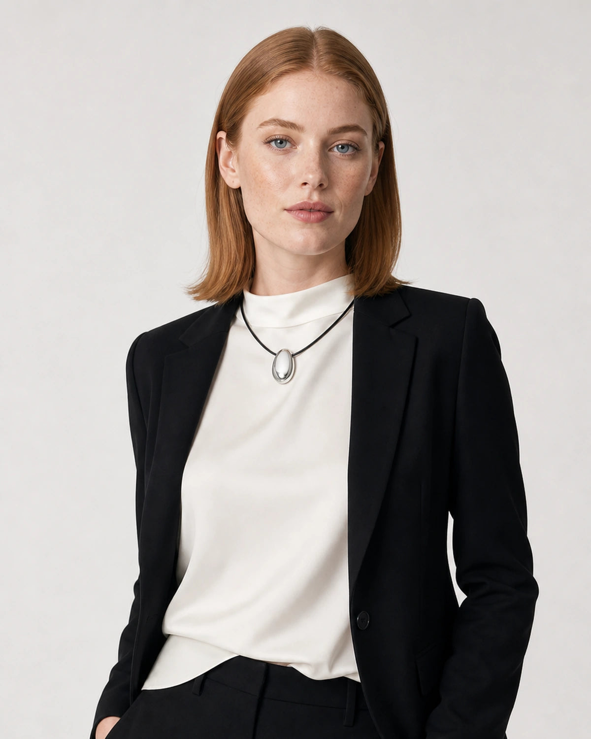 American model aged 25 wearing the Naiya silver pebble cord necklace in a pale dove-grey studio
