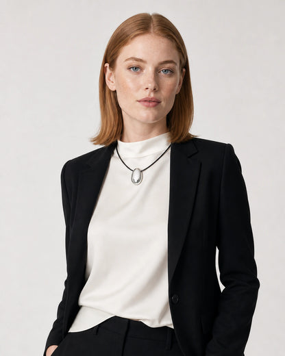 American model aged 25 wearing the Naiya silver pebble cord necklace in a pale dove-grey studio