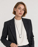 Human-scale studio view of the Naiya silver cord necklace with black tailoring