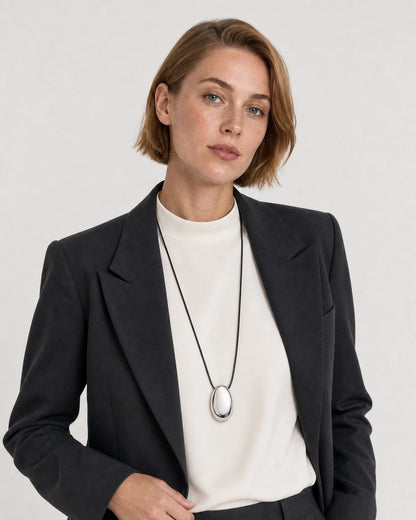 Human-scale studio view of the Naiya silver cord necklace with black tailoring