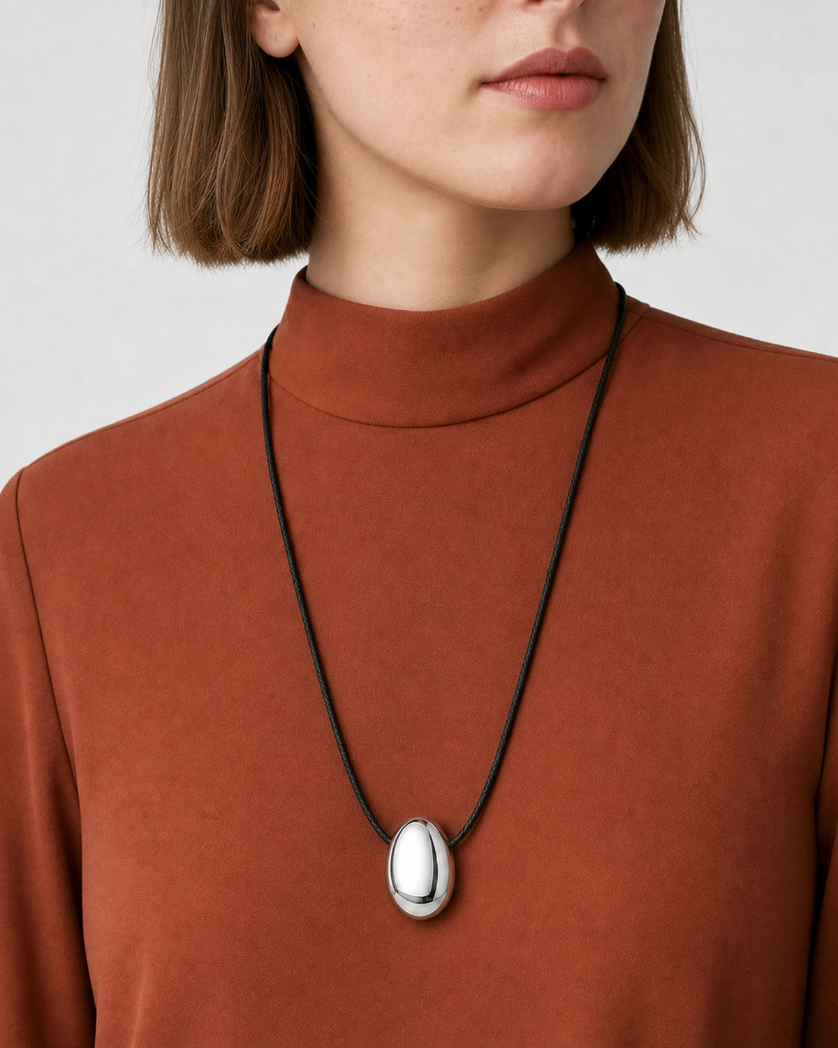 Three-quarter mouth-down portrait wearing the Naiya silver pebble cord necklace