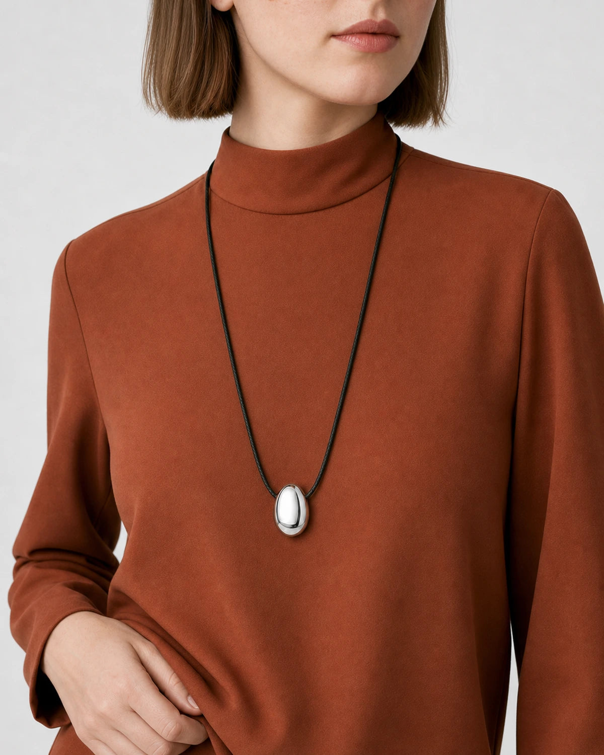 Eye-free upper-torso studio view wearing the Naiya silver pebble cord necklace