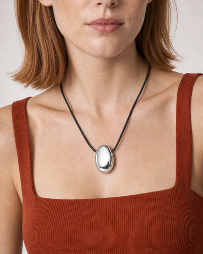 Close wearing view of the Naiya mirror-silver pebble and black braided cord
