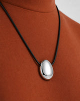 Oblique worn macro of the Naiya silver pebble and both direct side-threaded cord entries