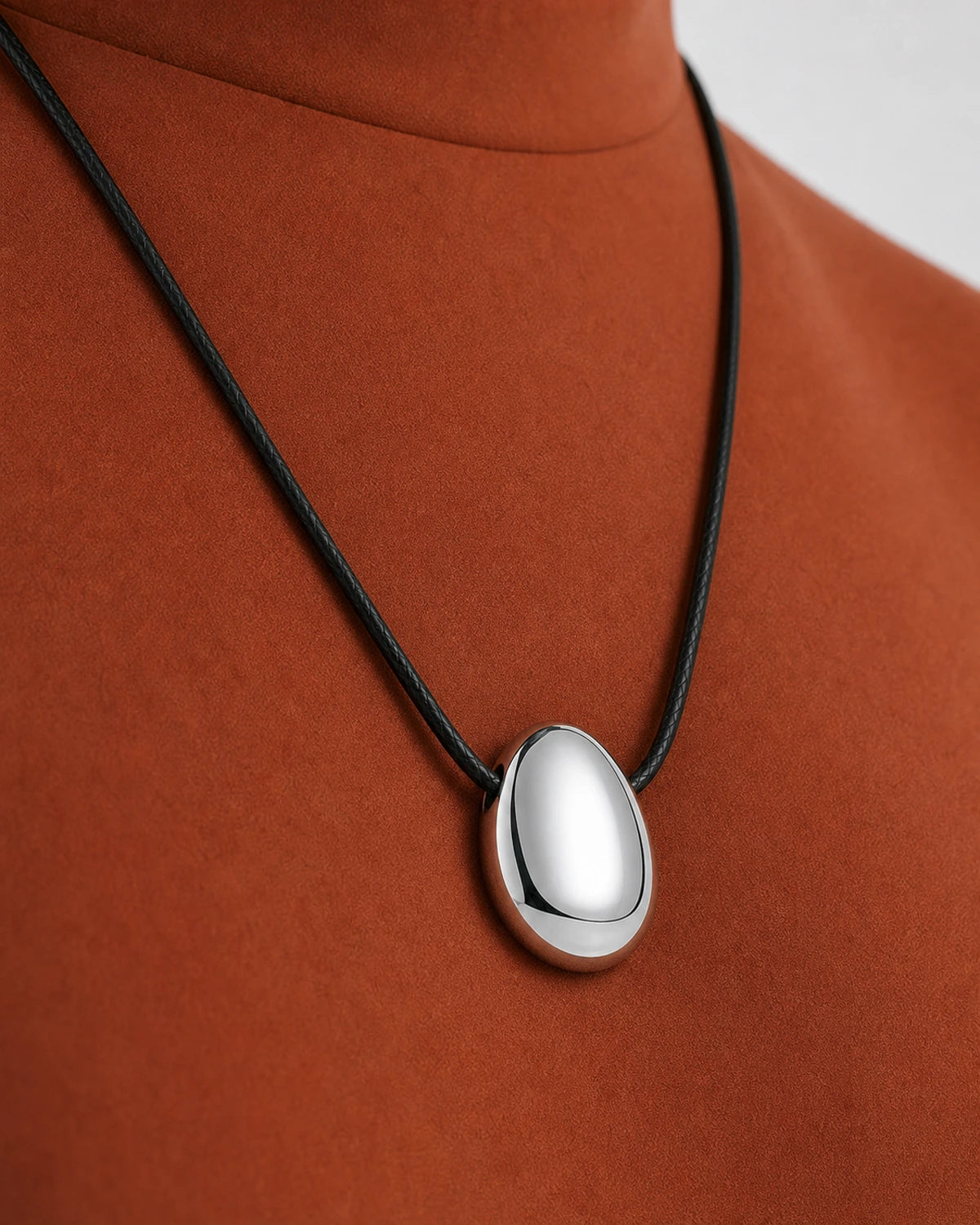 Oblique worn macro of the Naiya silver pebble and both direct side-threaded cord entries