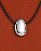 Frontal extreme worn macro of the Naiya mirror-silver pebble and black braided cord