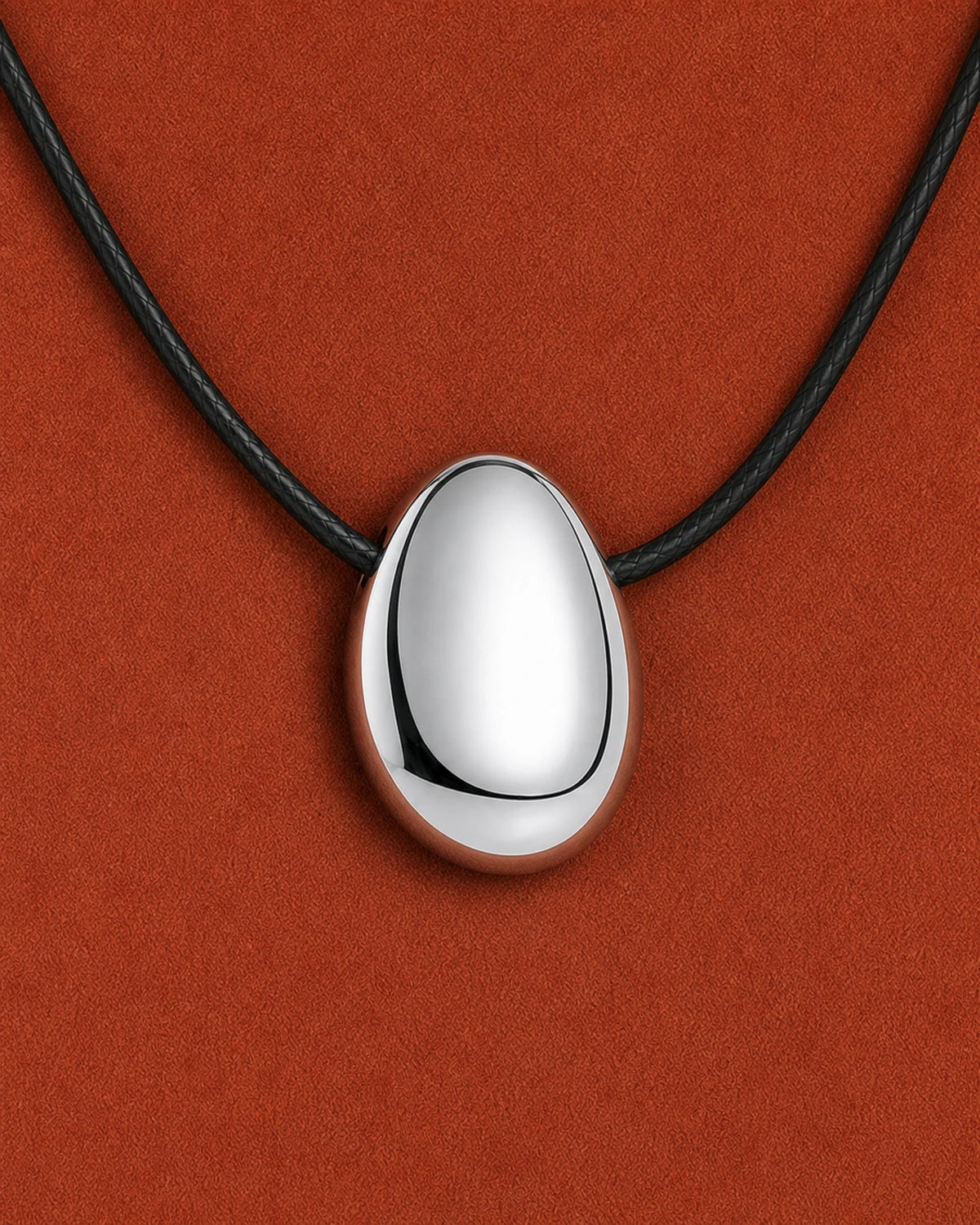 Frontal extreme worn macro of the Naiya mirror-silver pebble and black braided cord