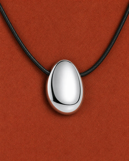 Frontal extreme worn macro of the Naiya mirror-silver pebble and black braided cord