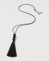 Alternate full-length view of the adjustable Nera black tassel necklace on pale dove-grey