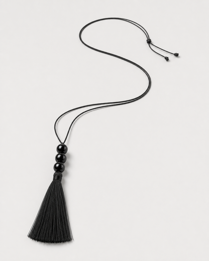 Alternate full-length view of the adjustable Nera black tassel necklace on pale dove-grey