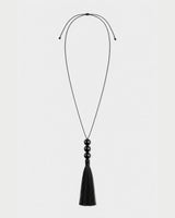 Nera black three-bead tassel necklace with adjustable cord on pale neutral grey