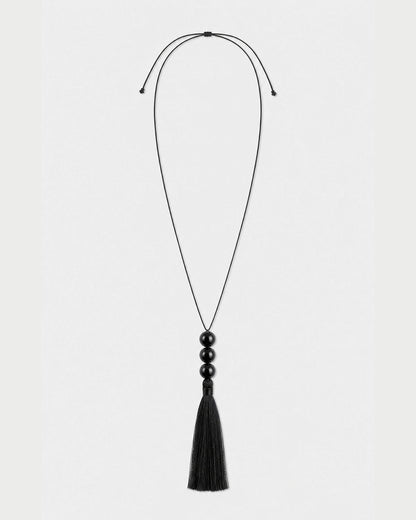 Nera black three-bead tassel necklace with adjustable cord on pale neutral grey