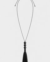 Nera black three-bead tassel necklace on a seamless pale dove-grey studio background