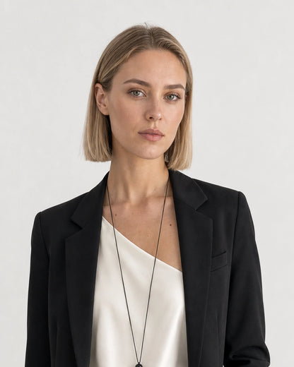British model aged 26 wearing the long Nera bead tassel necklace in a pale dove-grey studio