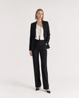 Wide studio portrait showing the Nera tassel necklace at natural scale with black tailoring