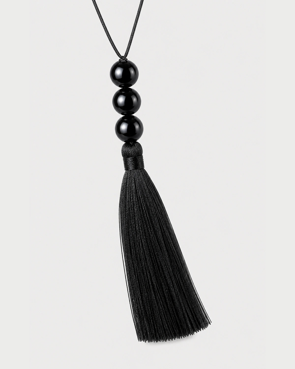 Straight macro of the Nera three glossy beads, wrapped neck and complete black tassel