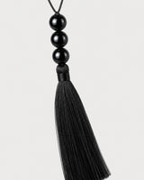 Macro detail of the Nera three glossy black beads and silk-look tassel