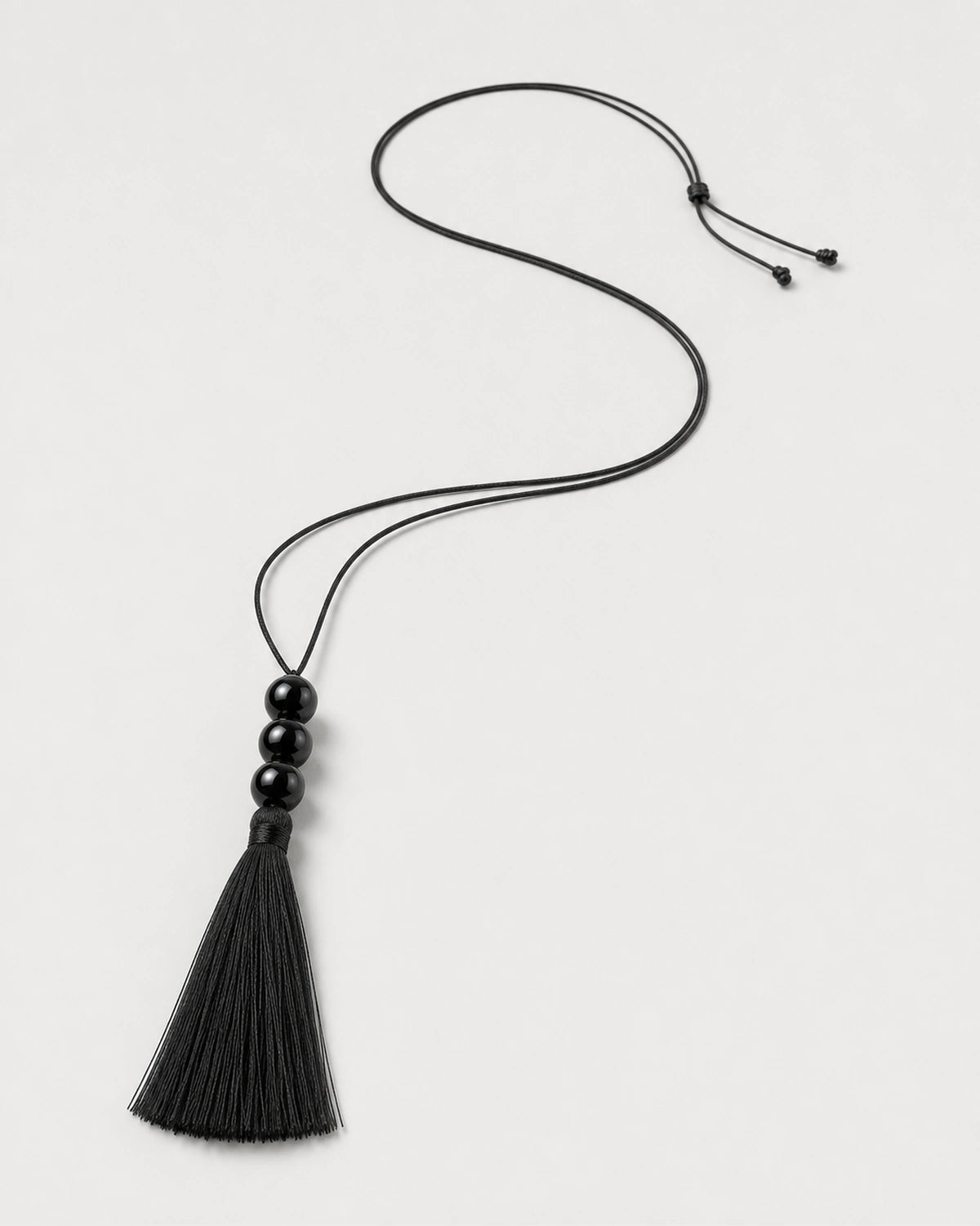 Alternate complete Nera black tassel necklace in an asymmetric curve with sliding knot and tails
