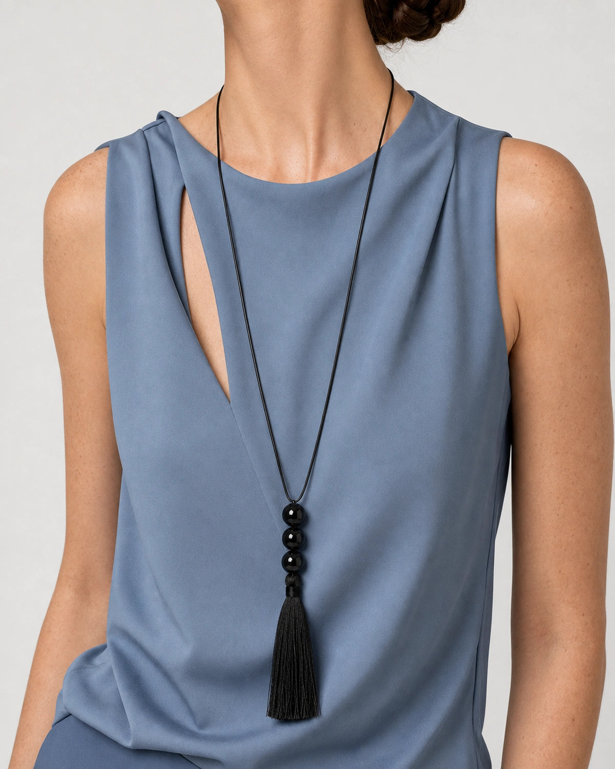 Rotated torso pose wearing the Nera three-bead tassel necklace