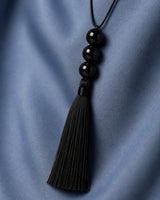Oblique worn macro of the Nera three equal beads, wrapped neck and tassel fibres