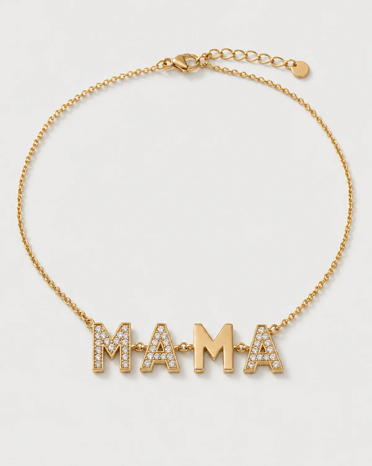 Noa gold articulated MAMA necklace on a seamless pale dove-grey studio background