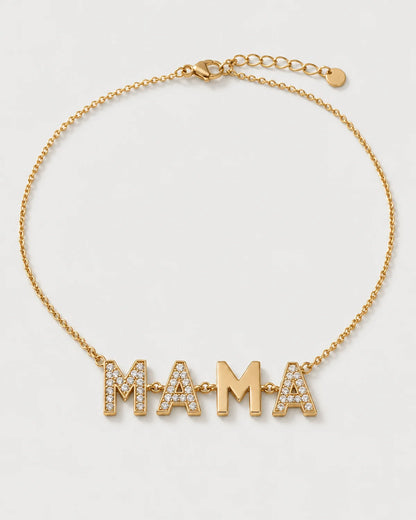Noa gold articulated MAMA necklace on a seamless pale dove-grey studio background
