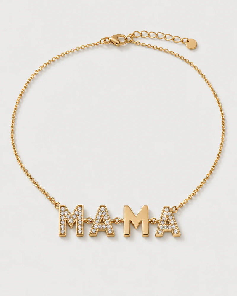 Noa gold articulated MAMA necklace on a seamless pale dove-grey studio background