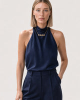 Wide editorial studio portrait showing the Noa MAMA necklace at natural scale