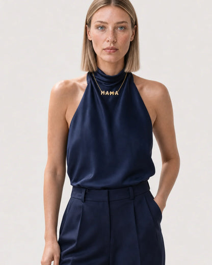 Wide editorial studio portrait showing the Noa MAMA necklace at natural scale