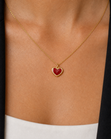 Extreme on-body macro of the Noémie raised gold rim and glossy crimson heart