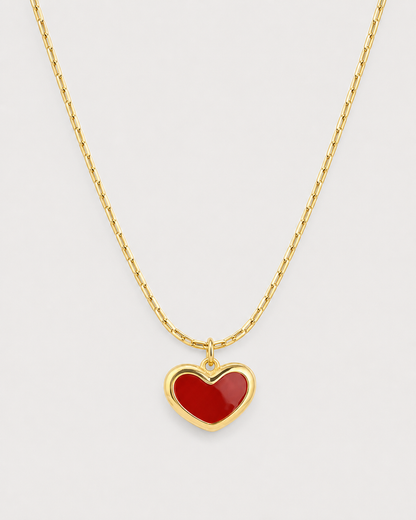 Macro of the Noemie glossy crimson heart, raised gold rim and fine bar-link chain