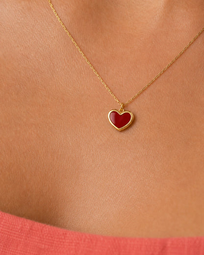 Extreme on-body macro of the Noemie raised crimson heart and polished gold rim
