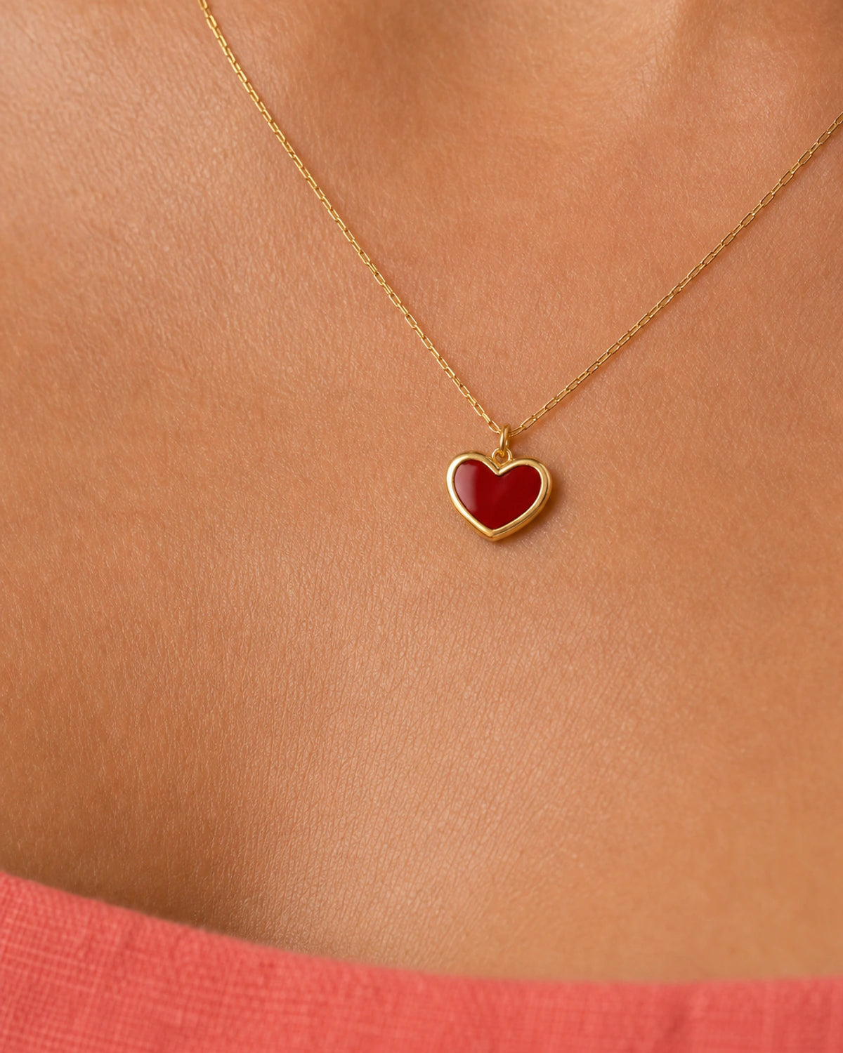 Extreme on-body macro of the Noemie raised crimson heart and polished gold rim