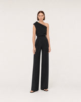 Wide studio portrait in a black one-shoulder look featuring Nysa earrings