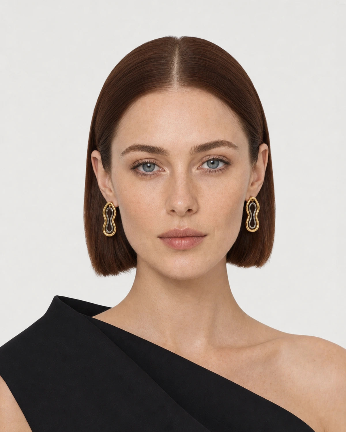 Model wearing Nysa mixed-metal studs in a pale dove-grey studio