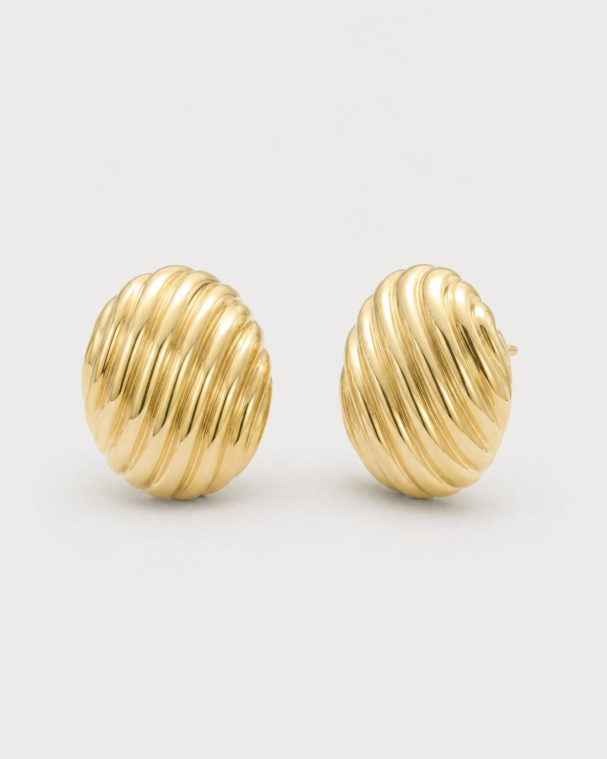 Odette gold ribbed oval stud earrings on pale dove-grey