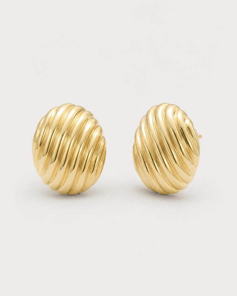 Odette gold ribbed oval stud earrings on pale dove-grey
