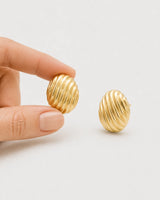 Hand-held scale view of the compact Odette gold oval studs