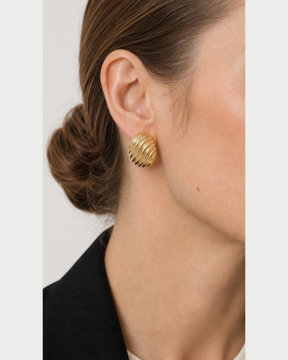 Extreme on-ear macro of the Odette gold ribbed oval stud