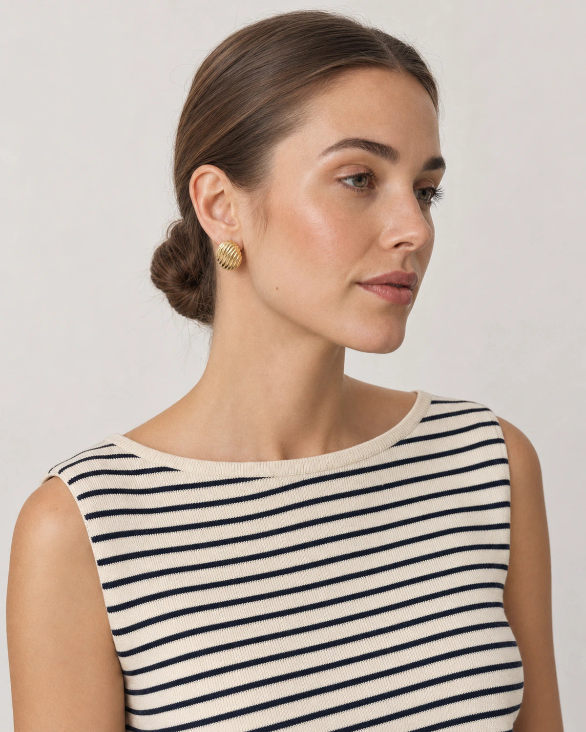 Model in a Breton summer knit wearing Odette gold ribbed oval studs