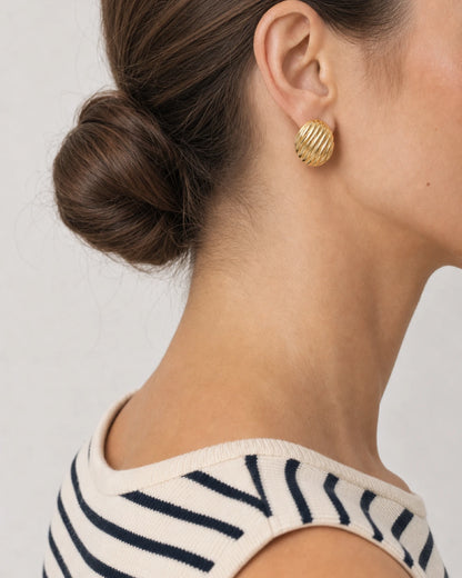 Eye-free rear portrait of Claudia wearing the convex gold Odette oval stud
