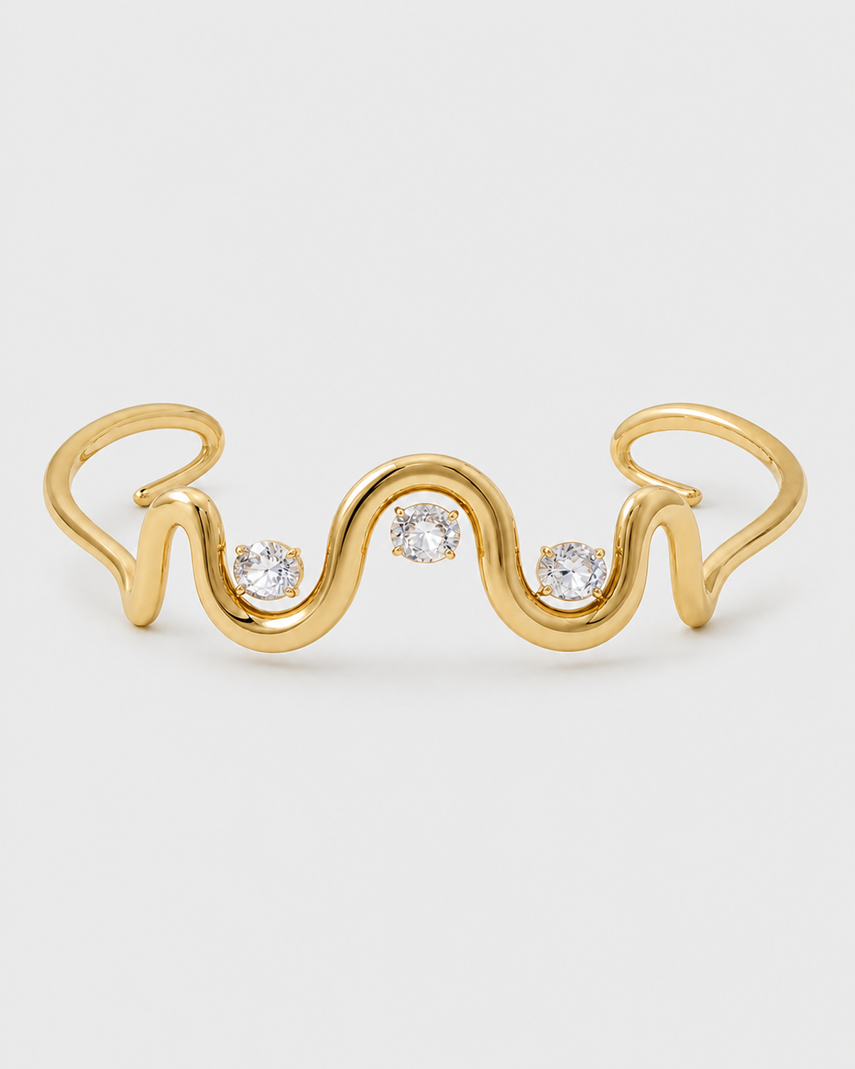 Onda gold crystal wave cuff on a seamless pale dove-grey studio background