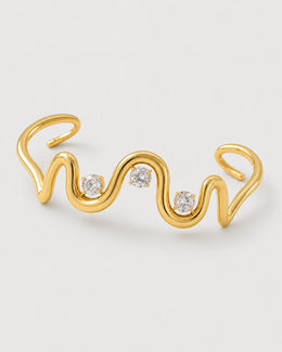 Macro detail of the Onda sculptural gold wave and exactly three four-prong crystal settings