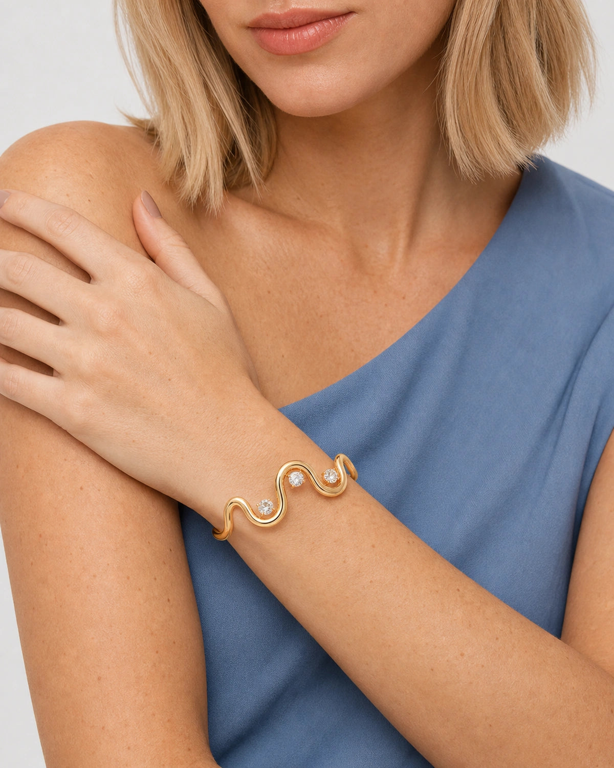 Mouth-down studio portrait wearing the Onda three-stone wave cuff across the upper arm