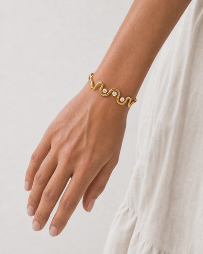 Close wearing view of the Onda gold wave cuff and three clear stones