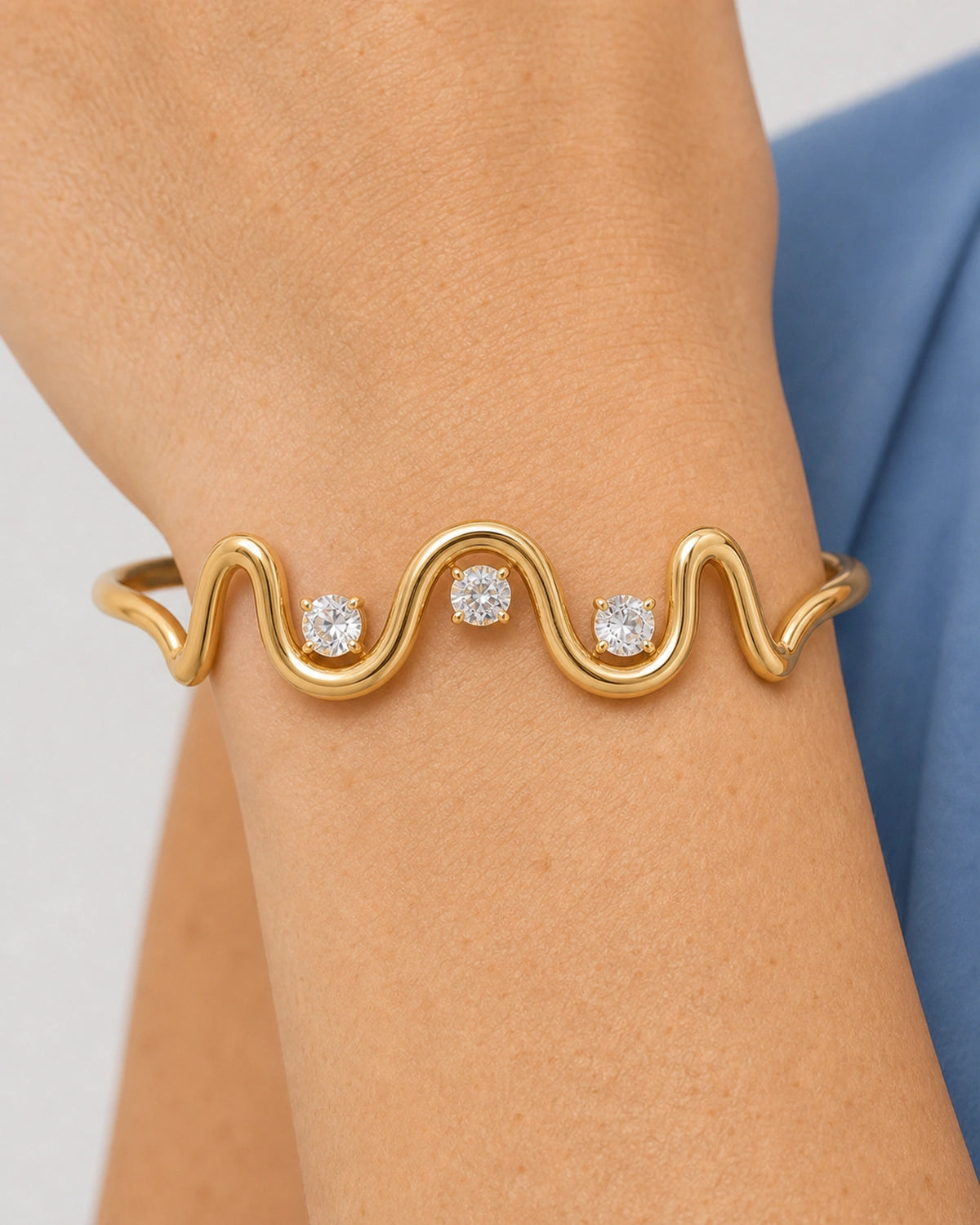 Complete worn macro of the Onda sculptural gold wave, three stones and both cuff shoulders