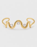 Onda gold crystal wave cuff with three clear stones on a pale neutral-grey studio background