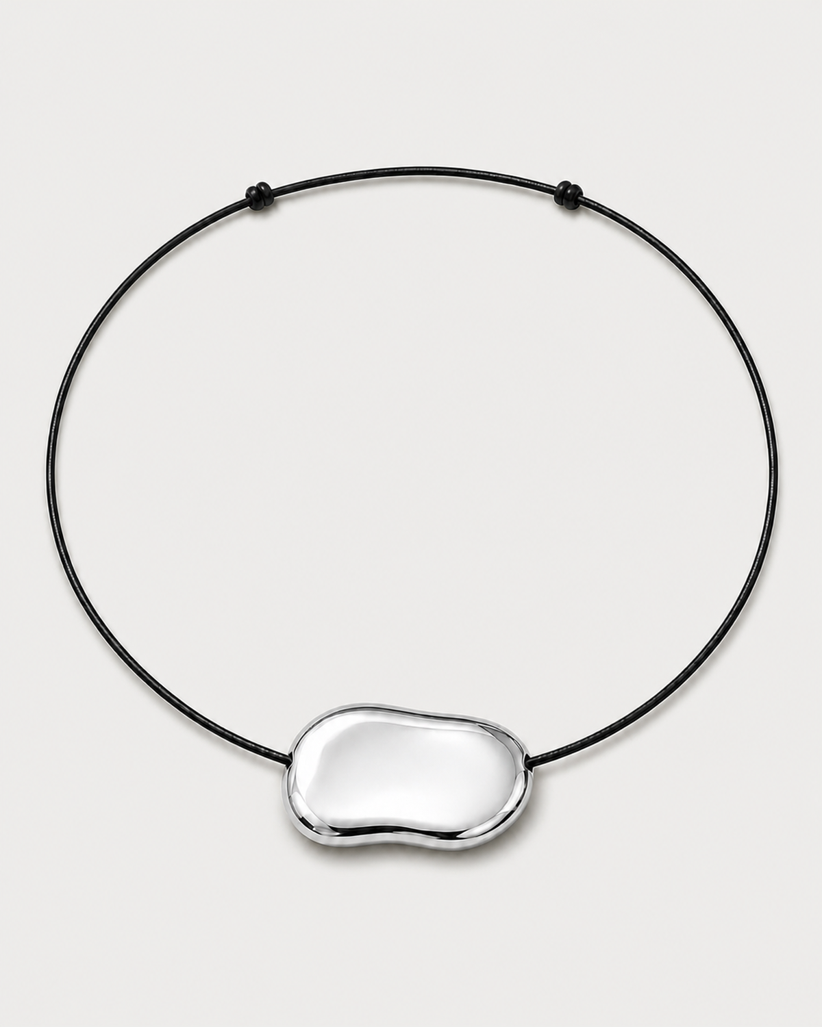Orra polished silver bean cord necklace on a seamless pale dove-grey studio background